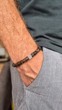 Load image into Gallery viewer, Close-up of a person wearing a beaded amber bracelet with a visible Vytis.