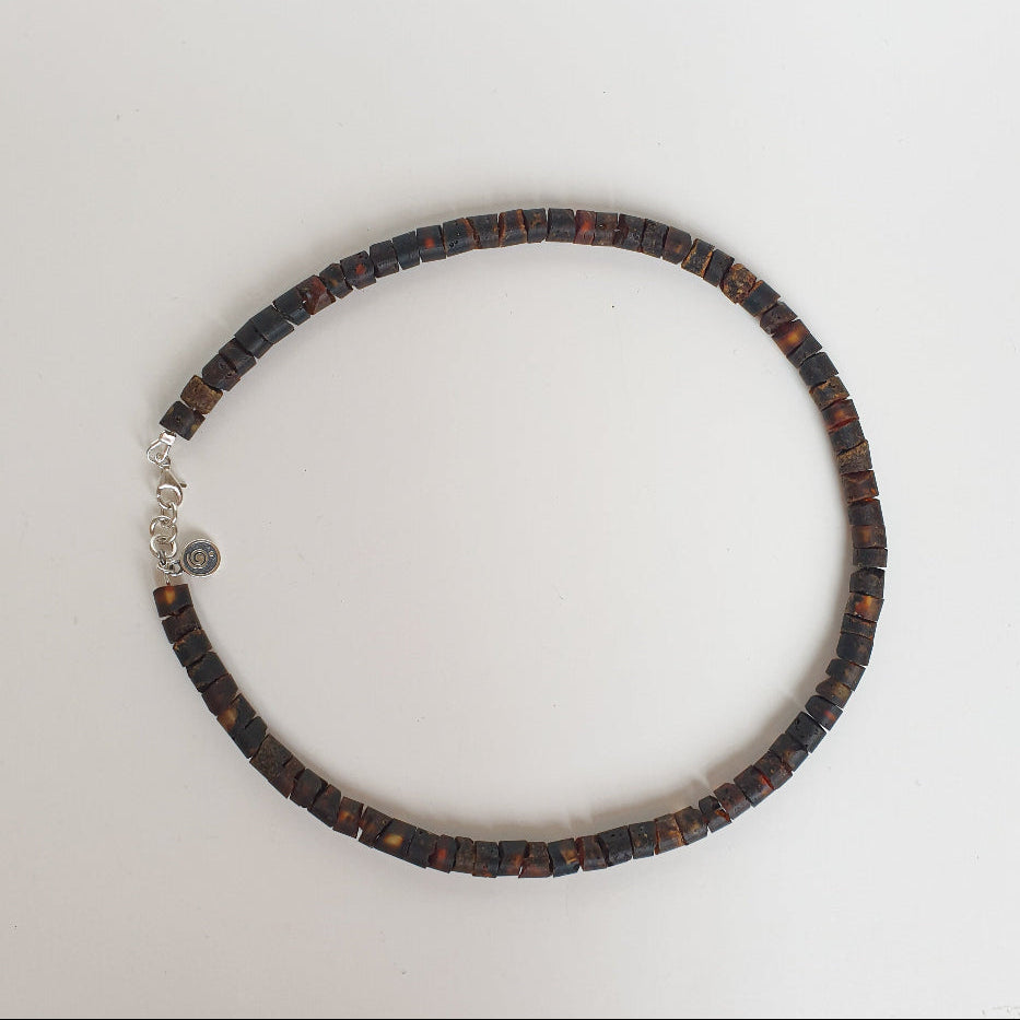 Amber necklace for men with a silver clasp on a light gray background
