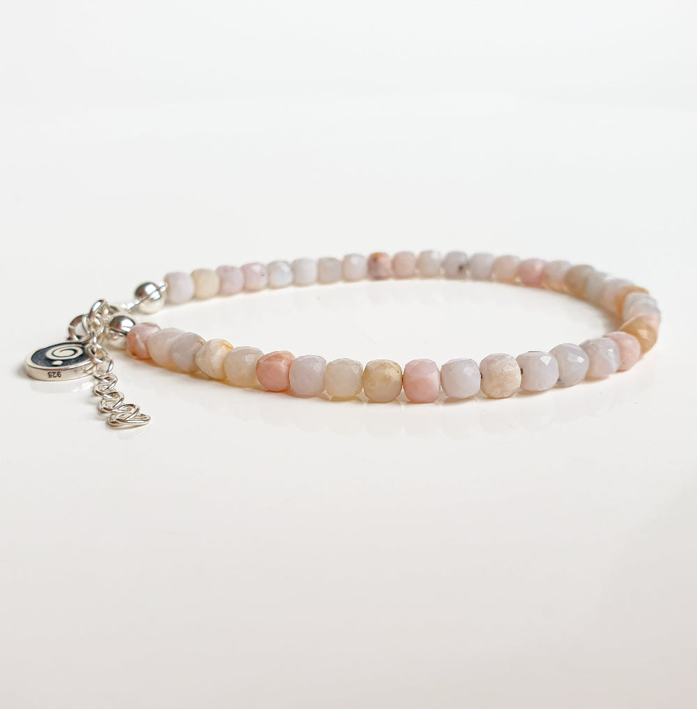 Beaded bracelet with a silver charm on a light background