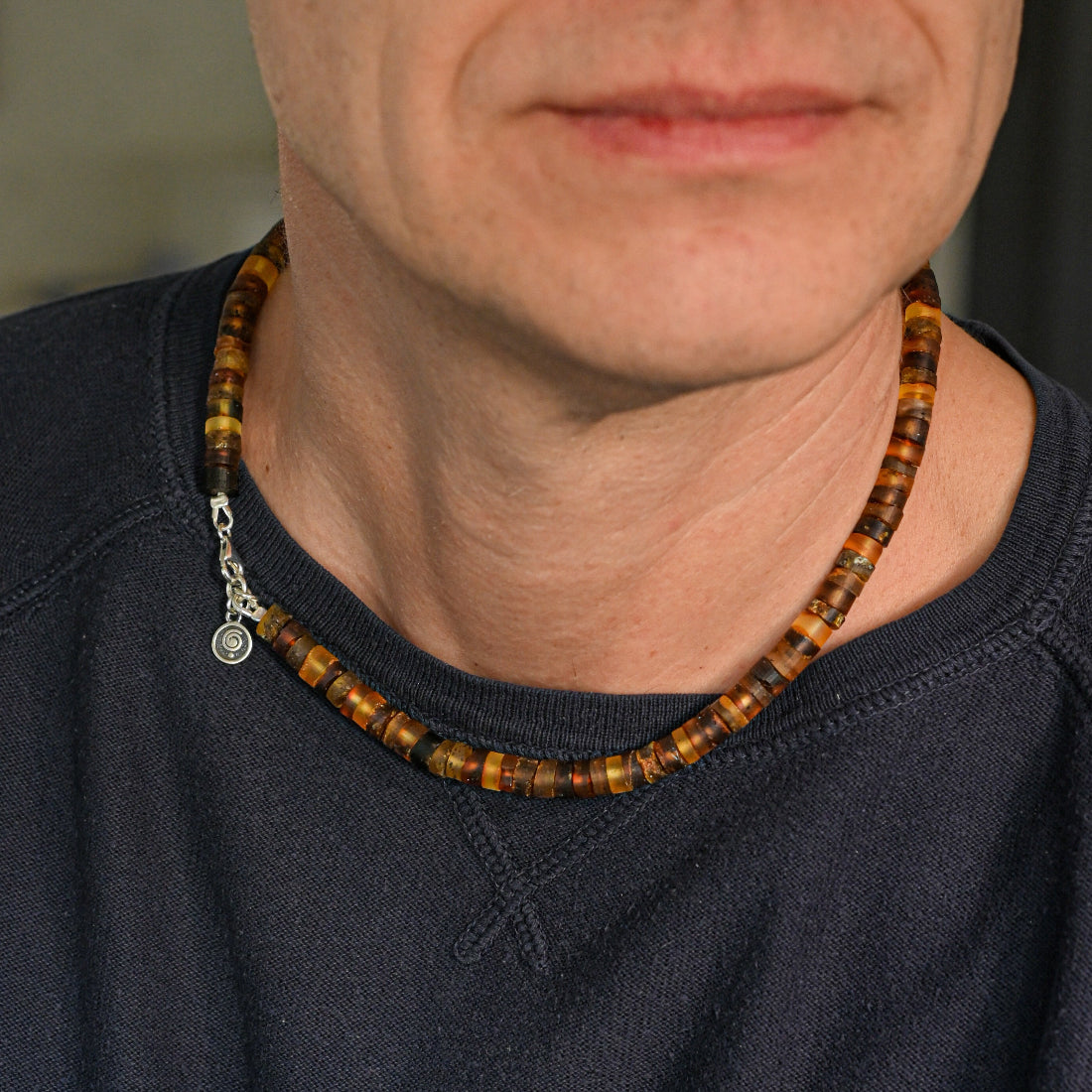 Close-up of a person wearing a beaded necklace with a dark shirt.