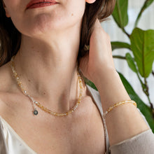 Load image into Gallery viewer, Woman wearing a delicate necklace and bracelet with a blurred green plant background