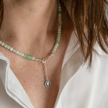 Load image into Gallery viewer, Close-up of a person wearing a green beaded necklace with a silver pendant.