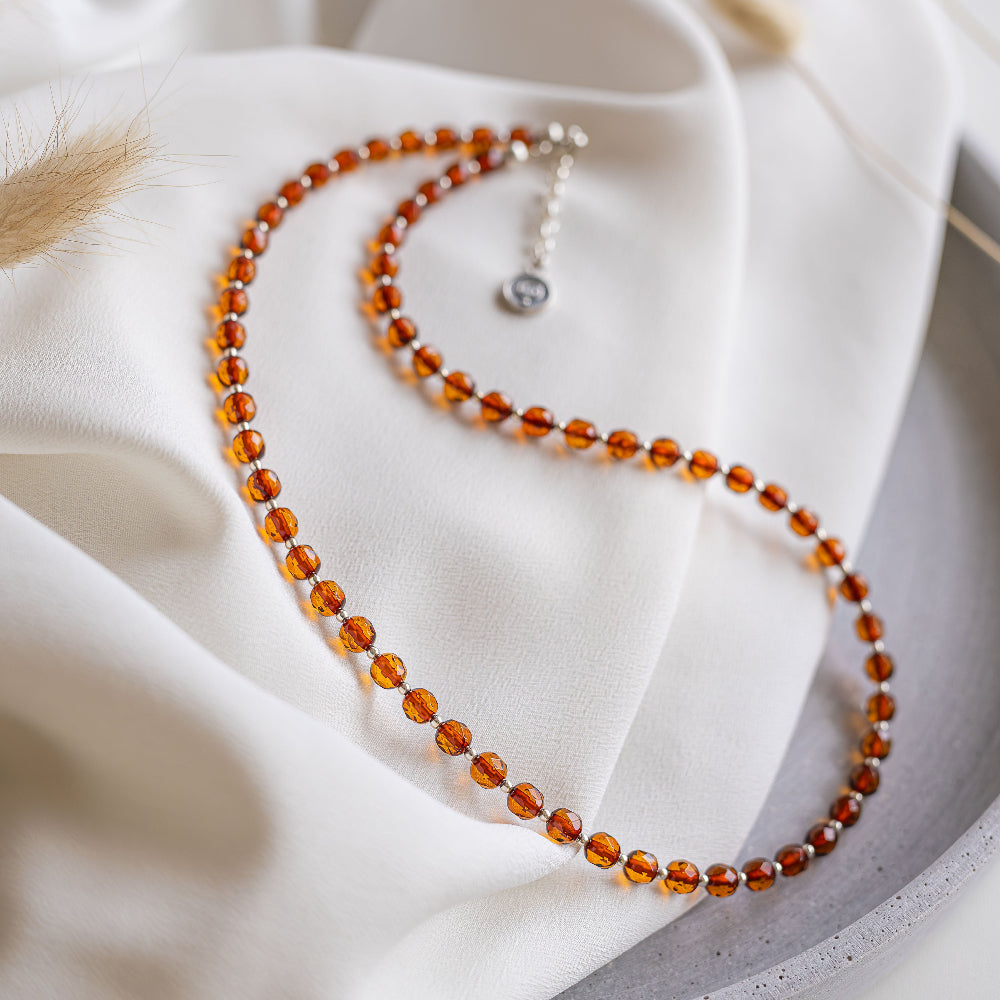 Necklace with amber beads on a white fabric background
