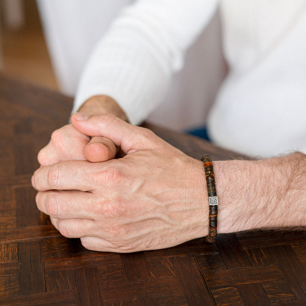 Close-up of a person's hands clasped together on a wooden surface