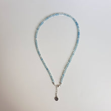 Load image into Gallery viewer, A beaded necklace with light blue aquamarine stones and a handmade silver medallion with a spiral design.